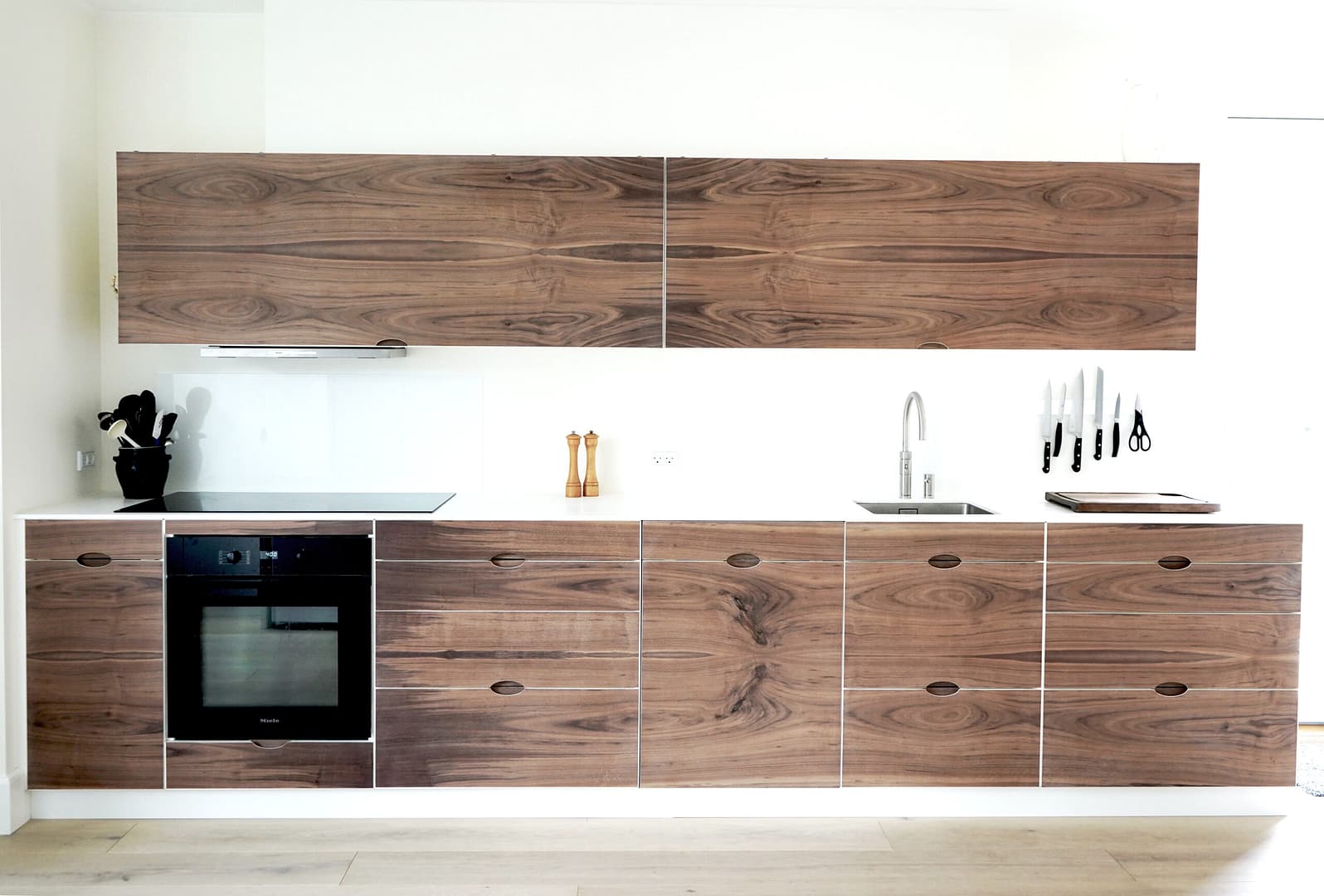 Snedkerkøkken med rene linjer håndlavet af valnød med corian bordplade, fremstillet lokalt hos Jesper Holm Design København.