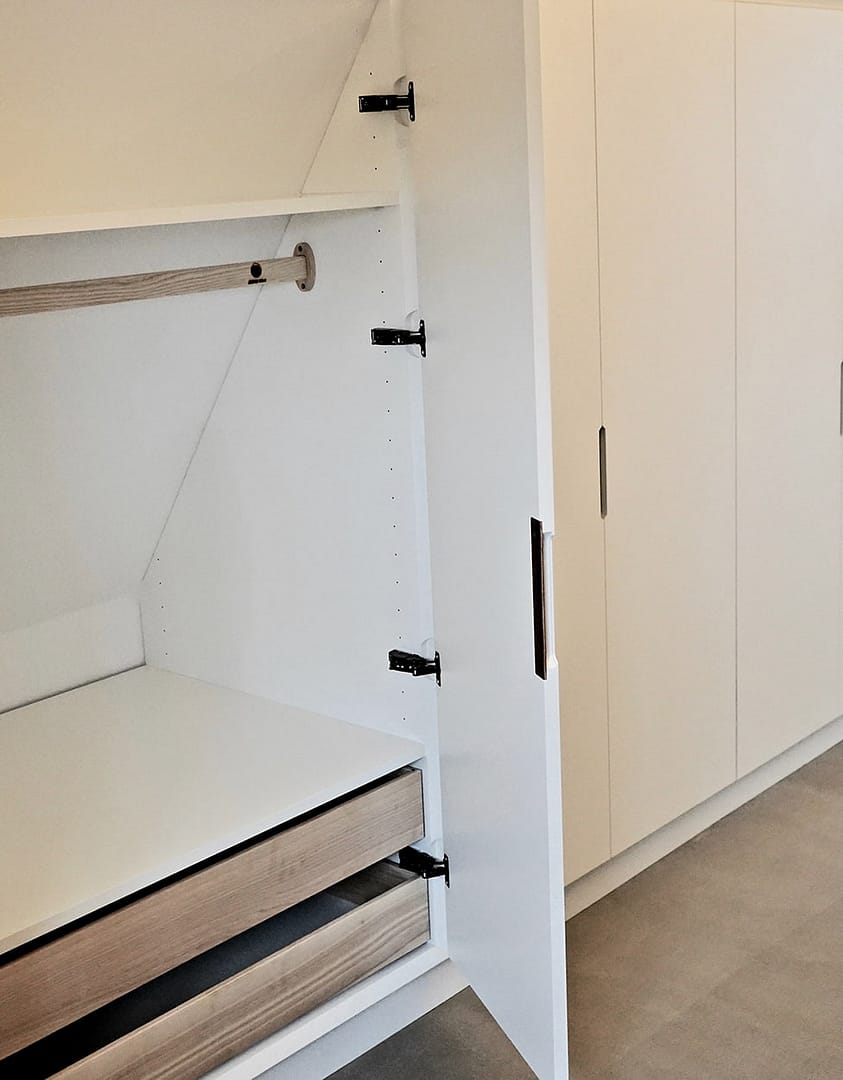 Skunkskabe under skråvæg indbygget efter mål af høj kvalitet, som kan holde livslangt og udnytter spildpladsen. Garderobeskabe med snedkerskuffer designes og fremstilles på mål hosnedkerkøkken højskabe med indvendig beklædning i valnød og lys i skabet. Få et personligt designet snedkerkøkken fremstillet til dine behov hos Jesper Holm Design i København.