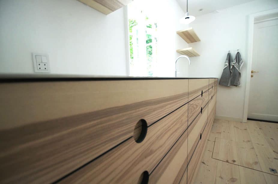 Snedkerskuffer i snedkerkøkken med gennemgående åretegninger, rene linjer og runde greb fra Jesper Holm Design i København.