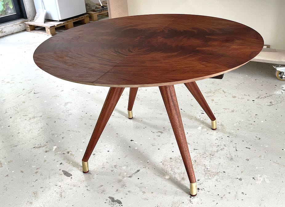 Mahogny rundt snedker spisebord med mønster i bordpladen af træets åretegninger. Varm træsort og messing. Specialdesignede snedkerborde håndlaves på snedkeriet Jesper Holm Design i København.